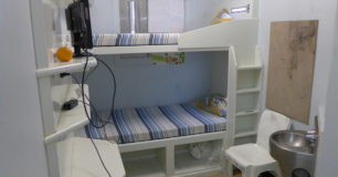 Photo of a double bunk bed cell with a chair and toilet