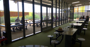 image of inside visits area, looking through the windows to the outside visits area also. Table and seating.