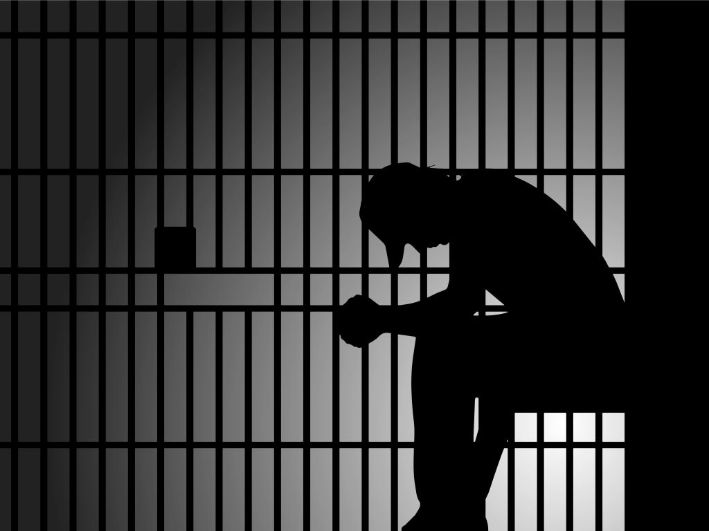 Image of a silhouette of a prisoner sitting down in a prison cell